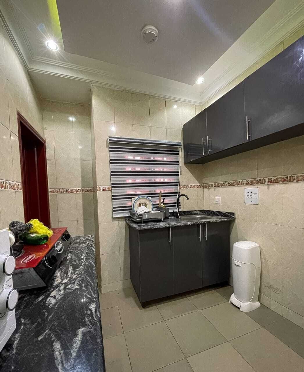 Uma cozinha compacta com bancada de mármore, pia embutida e um pequeno cesto de lixo.