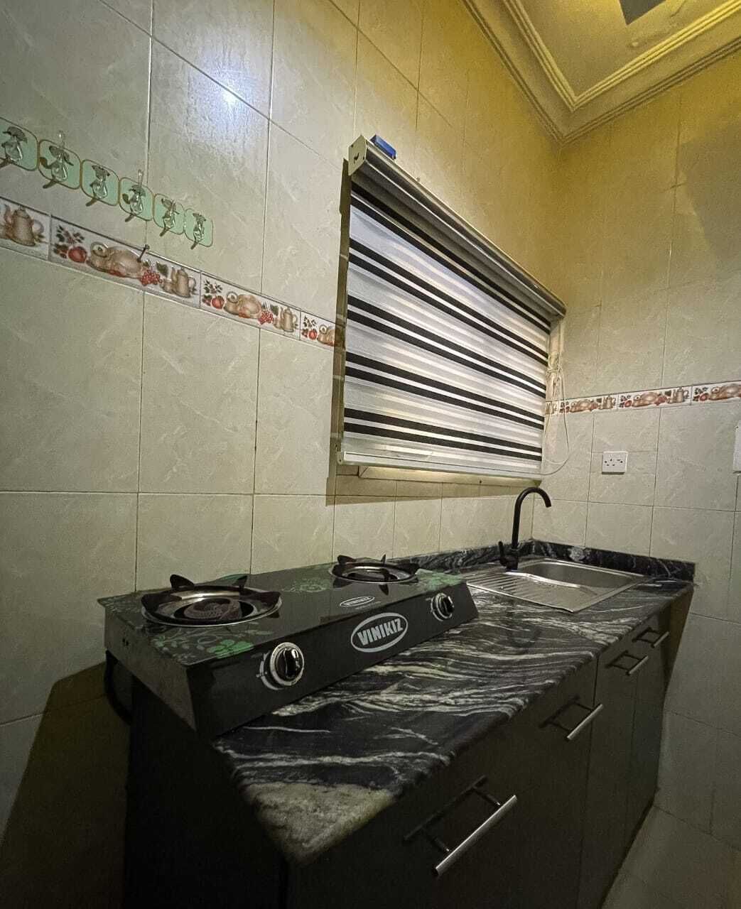 A kitchen with a gas stove, a sink, and a window with blinds.