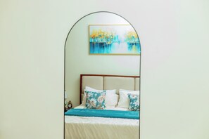 A bedroom with a bed, pillows, a painting, and a nightstand. - Modern Cozy Apartment, Fast WiFi & Balcony Views (Kampala)