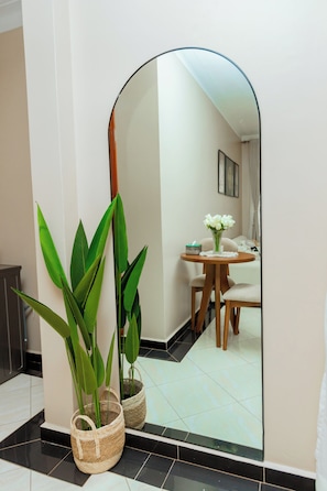 A mirror reflecting a dining area with a table, chairs, and a vase of flowers. - Modern Cozy Apartment, Fast WiFi & Balcony Views (Kampala)