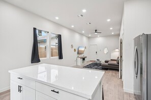 Eine moderne Küche mit einer großen Kochinsel, einem Essbereich mit einer Couch und einem Kühlschrank.