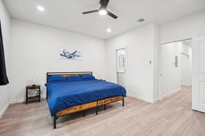 Ein Schlafzimmer mit einem Bett, einem Deckenventilator und einer Tür zu einem weiteren Raum.