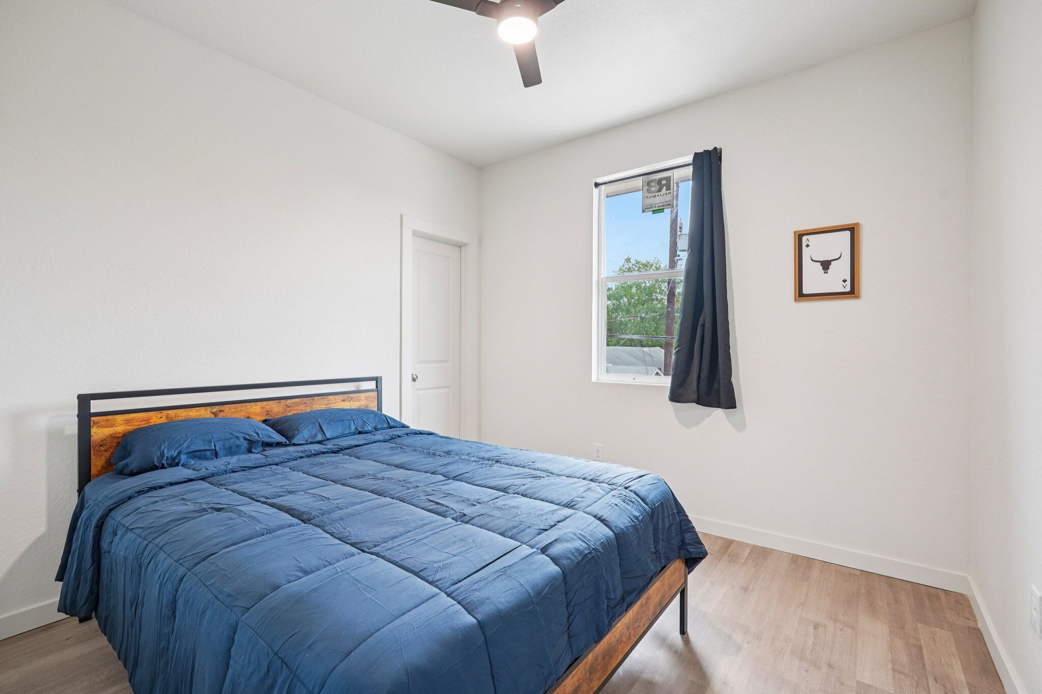 A bedroom with a bed, a window with a curtain, and a ceiling fan.