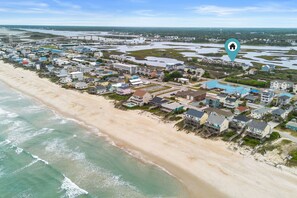 An aerial view of a coastal town with beachfront properties, a marina, and a bridge in the background. - Jolly Rogers: Oceanview, Walk to Beach, Sleeps 12 (Surf City)