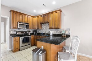A kitchen with wooden cabinets, a stainless steel stove, a microwave, and a granite countertop. - Jolly Rogers: Oceanview, Walk to Beach, Sleeps 12 (Surf City)
