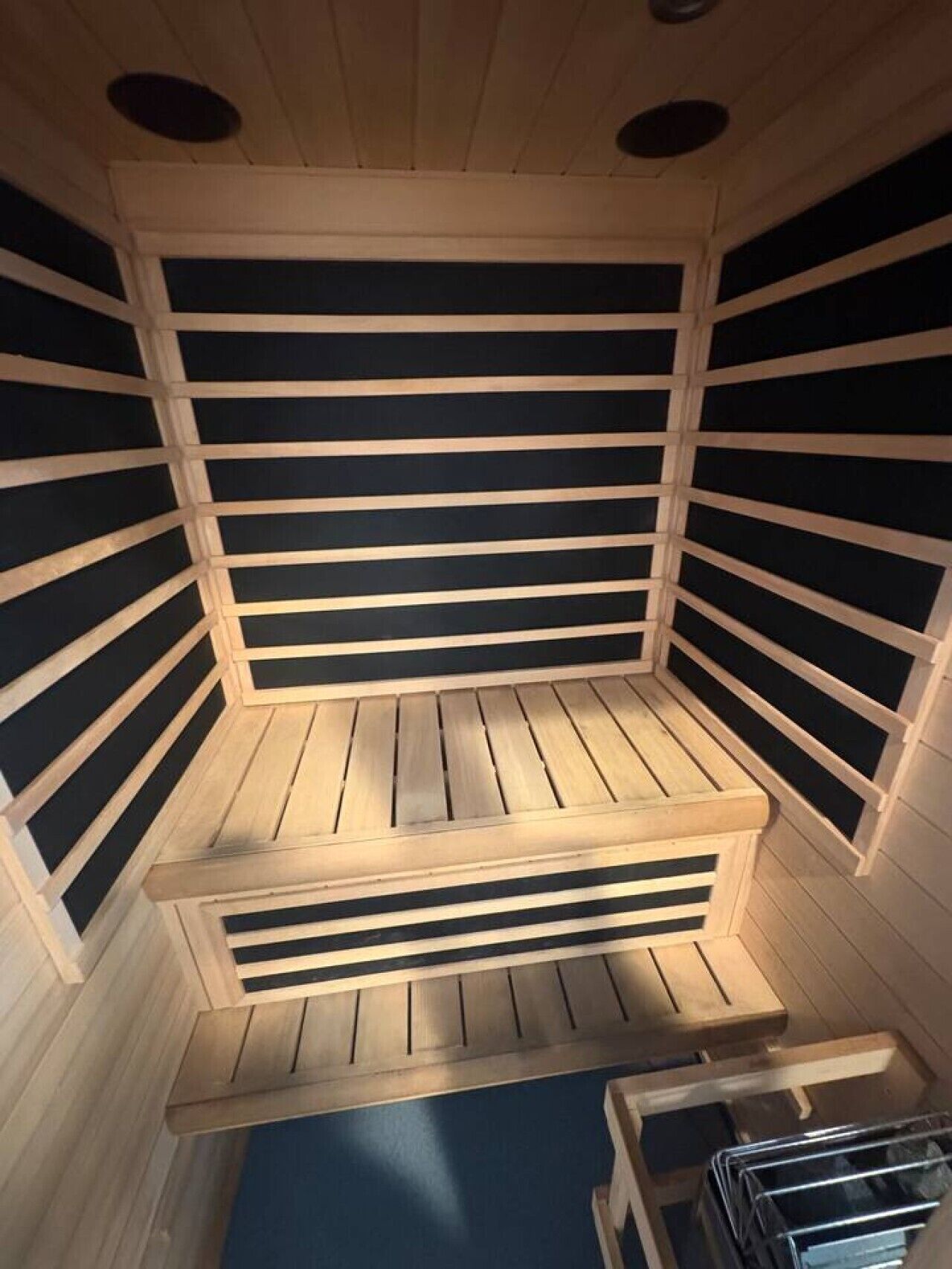 A sauna with a slatted wooden interior and a bench.