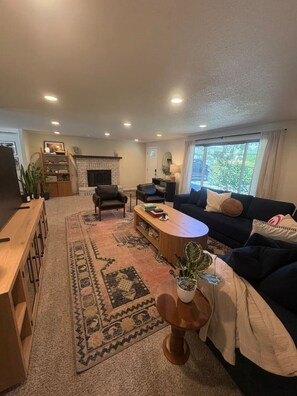 A living room with a fireplace, a sofa, a coffee table, and a TV. - Private Resort • Pool, Spa + Sauna (Grants Pass)