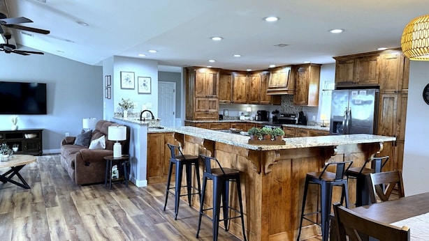 Una cocina moderna con armarios de madera, encimera de granito y una isla integrada con taburetes de bar.