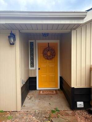 A yellow door with a wreath, a welcome mat, and a lantern outside a building. - Bike to Coler - Private Backyard - Big Kitchen:  The Roost - Bentonville, AR (Bentonville)
