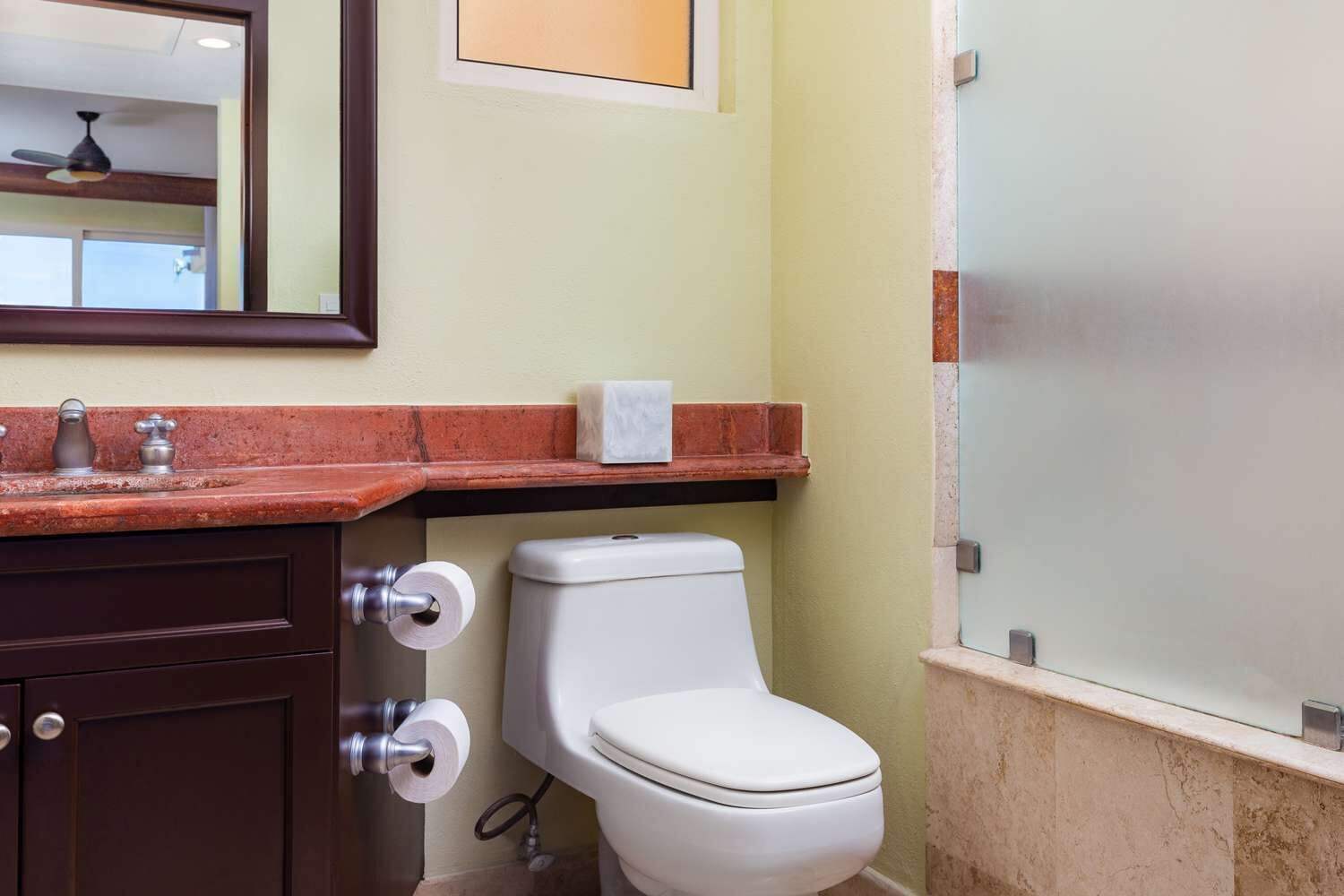 A bathroom with a toilet, a sink with a mirror, and a towel rack.