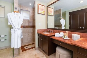 A bathroom with a marble floor, a large mirror, a sink with a marble countertop, and a robe hanging on a rack. - Cozy 2-bedroom condo in charming Bucerías with AC and fitness room (Bucerías)