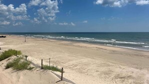 Ein Strand mit blauem Himmel, Wellen und einem Zaun.