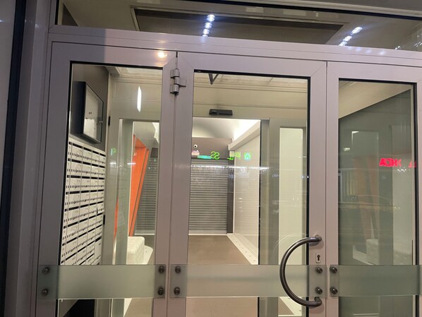 Ein modernes Interieur mit Glastür, Metallgriffen und einem sichtbaren Korridor mit heruntergelassenem Rollo.