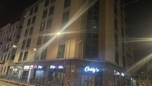 Un edificio de varios pisos con un letrero llamativo de Caddy's al nivel de la calle.