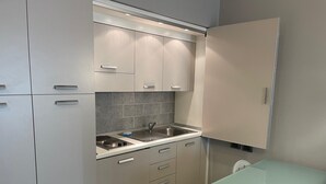 Una cocina compacta con un lavamanos, armarios y una pequeña mesa.