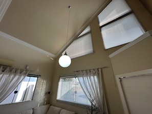 A room with a sloped ceiling, multiple windows with blinds, a hanging light fixture, and a radiator. - Complete and cozy house for 7 people. (Maringá)