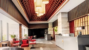 A spacious lobby with a reception desk, seating area, and large windows. - The Trinity Mandala Seaview (Mui Ne)