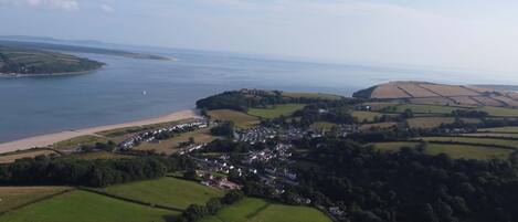 An aerial view of a coastal village with fields, a beach, and a small town.