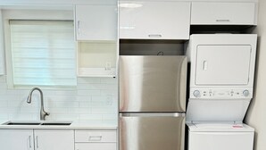 Una cocina moderna con armarios blancos, un refrigerador de acero inoxidable y un horno empotrado.