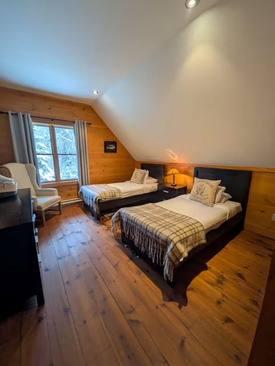 Un dormitorio acogedor en el ático con dos camas, un escritorio y una silla.