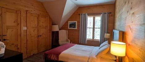 Una habitación de madera con una cama, un escritorio y una ventana.
