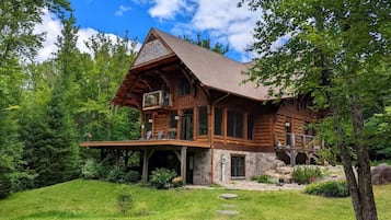A log cabin with a stone foundation, a porch, and a large window.
