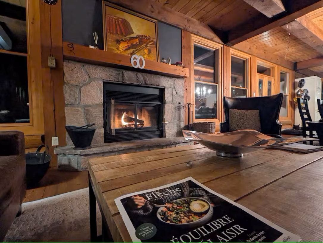 A cozy room with a stone fireplace, wooden furniture, and a magazine on the table.