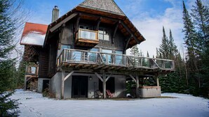 A wooden cabin with a balcony, surrounded by snow and trees. - Spacious family 5 Bedroom Chalet, Hot Tub, pet-friendly, pool lake tennis (Lac-Supérieur)