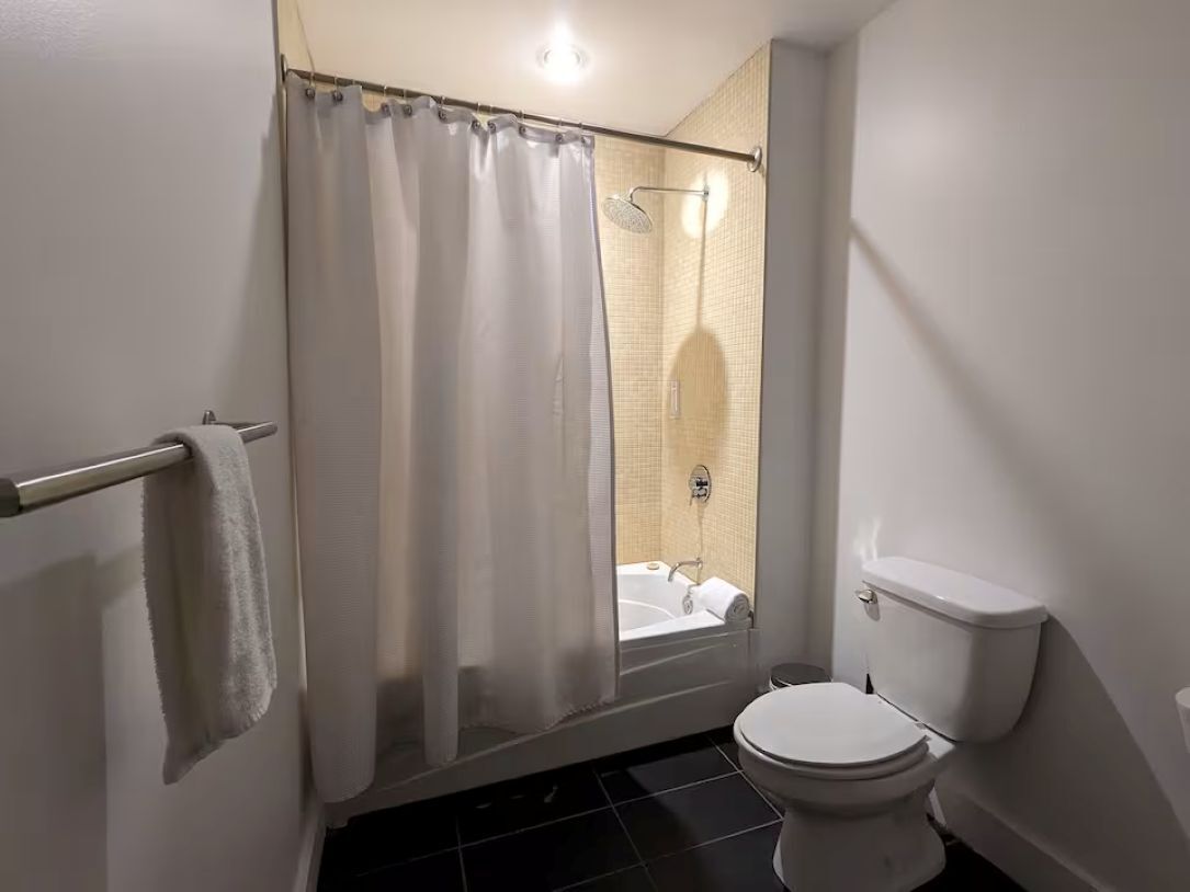 Un baño con ducha, inodoro y toallero.