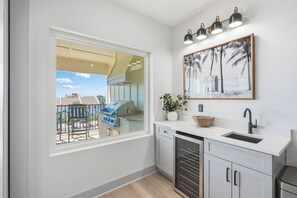 Eine Küche mit eingebautem Grill, einem Fenster mit Blick auf einen Balkon und einer wandmontierten Leuchte.