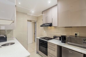 Een moderne keuken met een vaatwasser, fornuis, magnetron en koffiezetapparaat.