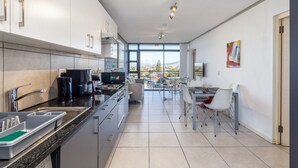 A modern kitchen with a dining area, large windows, and a view of the city. - Key West 314 by CTHA (Cape Town)