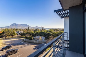 Ein Balkon mit Blick auf einen Parkplatz, ein Gebirge und eine Wohngegend.