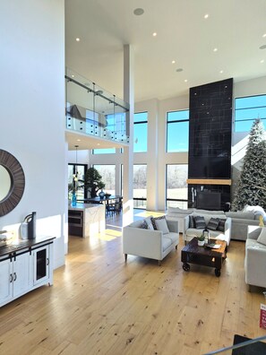 A spacious living area with a high ceiling, a fireplace, and a Christmas tree. - Forest Edge Luxury  Estate (Puslinch)