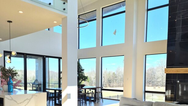 Un vaste espace de vie doté d’un haut plafond, de grandes fenêtres et d’un aménagement intérieur moderne.