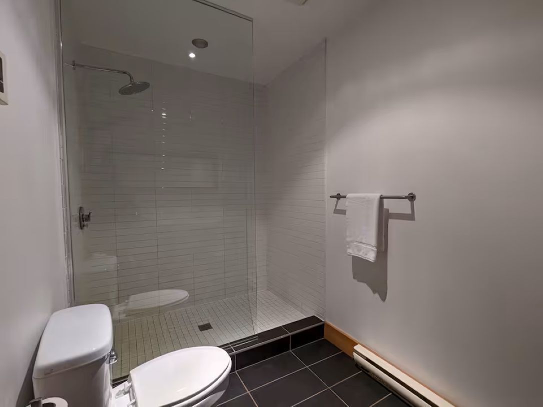 A bathroom with a toilet, a shower with a glass door, and a towel rack.