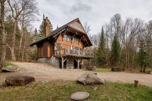 Eine Blockhütte mit Balkon, umgeben von Bäumen und Felsen.