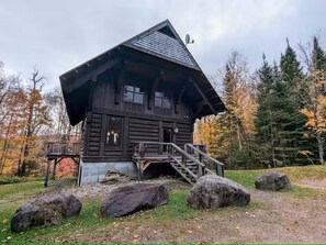 Ein rustikales Blockhaus mit steilem Dach, einer Veranda und einer Treppe zum Eingang.