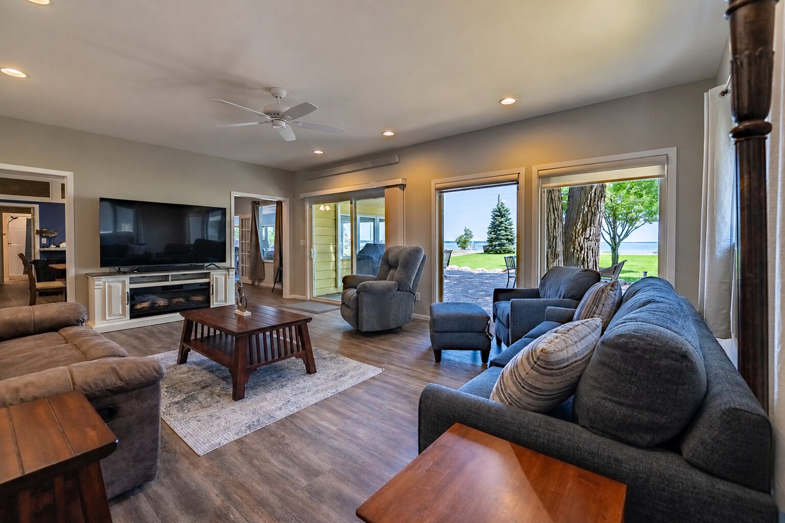 A spacious living room with a flat-screen TV, comfortable seating, and a view of the outdoors.