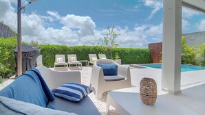 Ein Poolbereich mit Liegestühlen, einem überdachten Grillplatz und Blick auf den Pool.