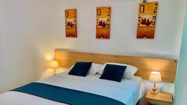 A bed with a wooden headboard, two bedside lamps, and a blue bedspread. - HOTEL CASA LATINA MANTA (Manta)