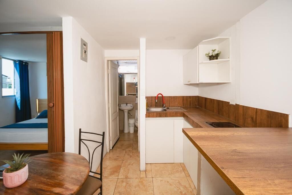 A compact kitchen with a wooden countertop, a sink, and a white cabinet.
