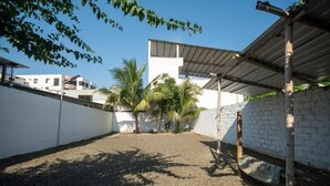A courtyard with a gravel ground, white walls, and a metal roof structure. - HOTEL CASA LATINA MANTA (Manta)