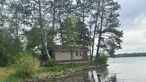 A cabin by a lake surrounded by trees.