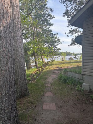 Um caminho leva a uma casa com vista para um lago e árvores.