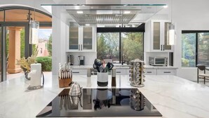 A modern kitchen with a central island, stainless steel appliances, and large windows offering views of the outdoors. - Chapel Showstopper! Walk to trails, Private yard (Sedona)