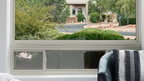 A room with a large arched window overlooking a mountain and greenery. - Chapel Showstopper! Walk to trails, Private yard (Sedona)
