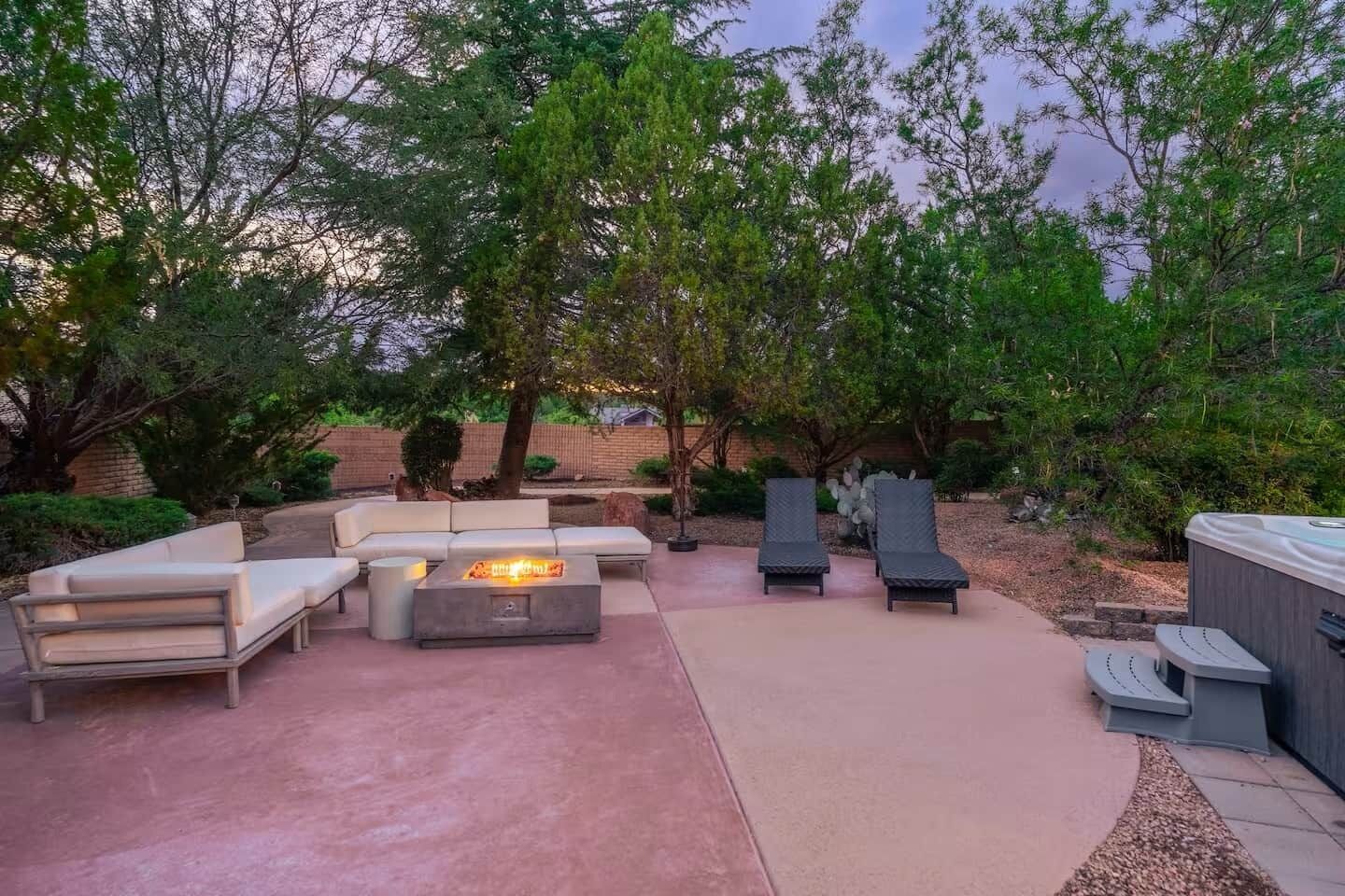 A patio with a fire pit, lounge chairs, and a sofa.