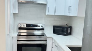 A modern kitchen with white cabinets, stainless steel appliances including a double oven and microwave, and a tiled backsplash. - 🏡 Upscale COZY 2BR Coastal Suite  Private Entry, Laundry & Minutes to the Beach (Surrey)