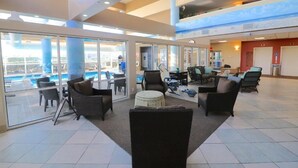 Un amplio espacio interior con vista a la piscina, ventanas grandes y varias zonas de estar.